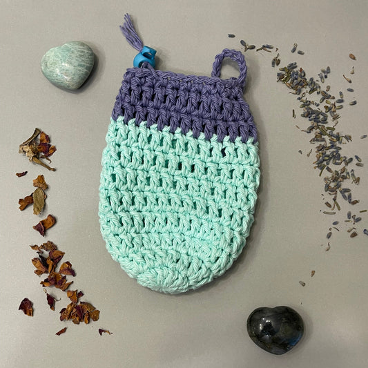 Crocheted soap bag with lavender buds and stones on a neutral background