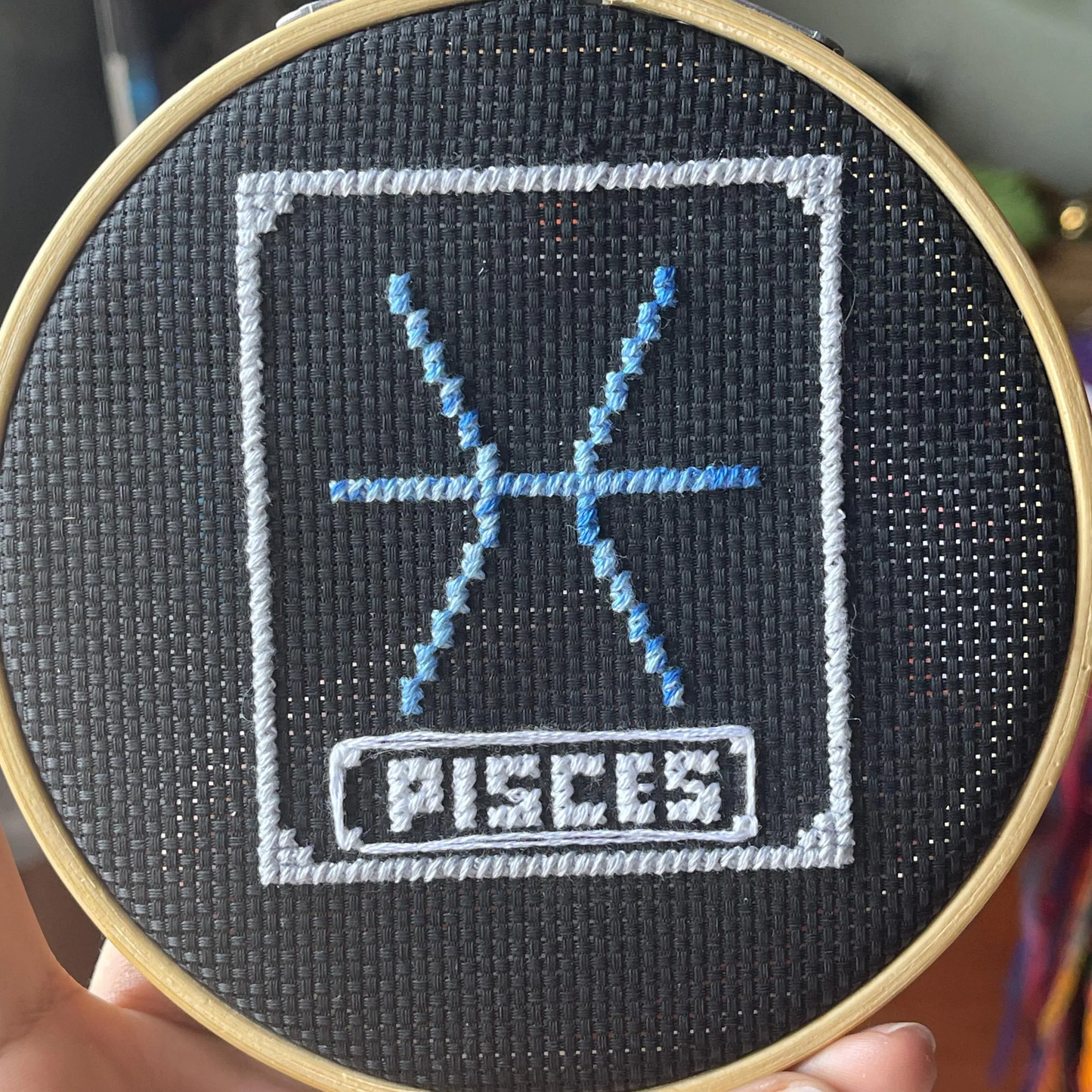 Embroidery hoop with Pisces zodiac sign design on black fabric