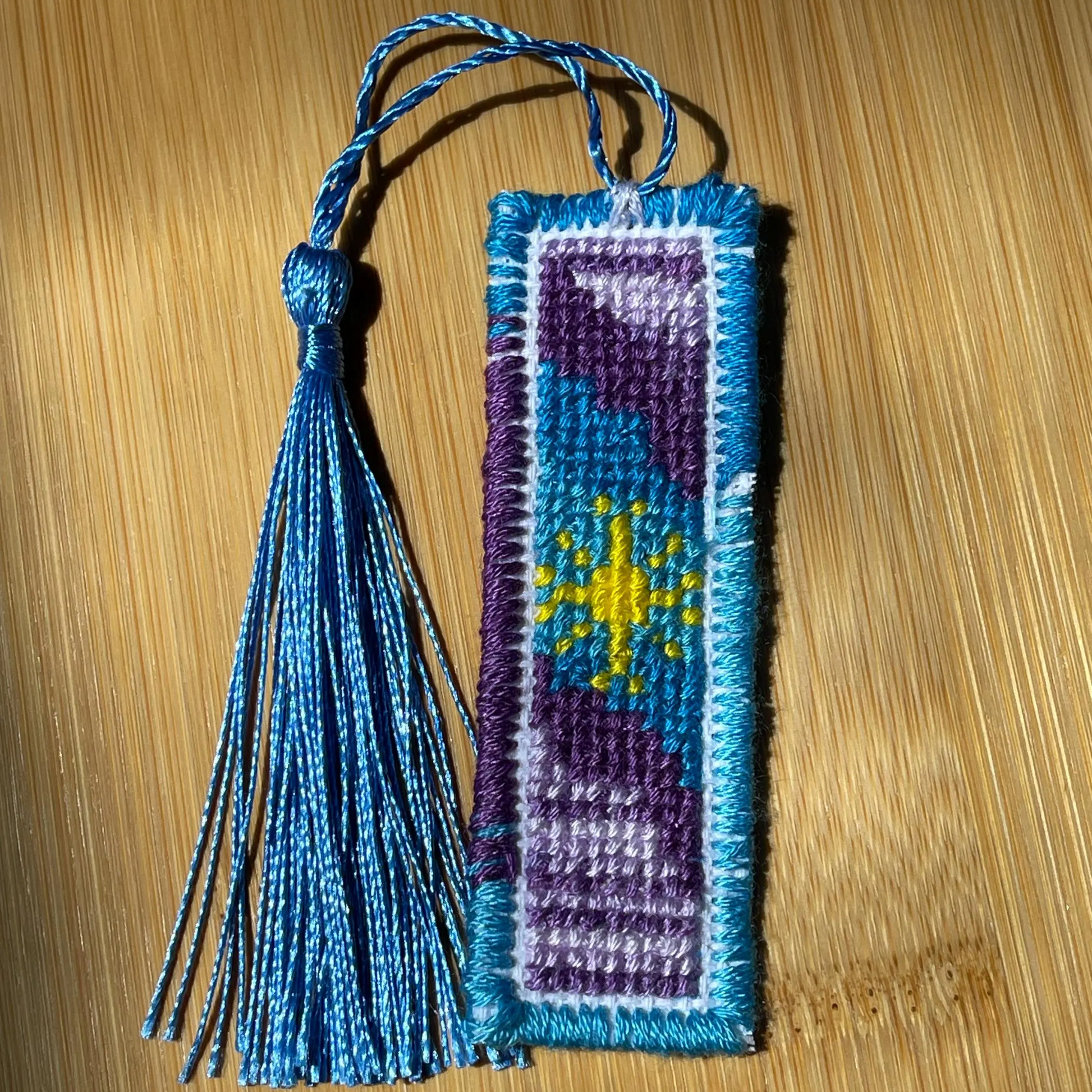 Handmade bookmark with blue tassel on a wooden surface