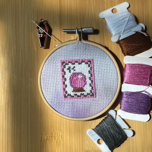 Embroidery hoop with a completed cross-stitch design on a wooden surface.
